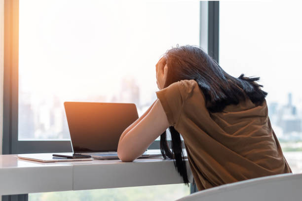 donna in attacco di panico, persona emotiva depressa stressante con disturbo d'ansia malattia della salute mentale, mal di testa ed emicrania seduta sulla scrivania del computer portatile - hard life foto e immagini stock