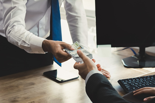 Businessman receiving money from his partner at working desk in the office - loan, bribery and corruption concepts