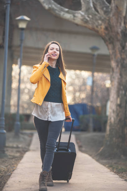 istock Young woman with suitcase talking on mobile 1137845939