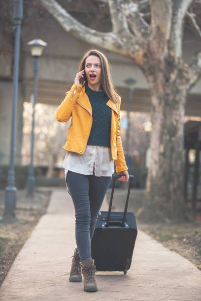 istock Young woman with suitcase talking on mobile 1137846205