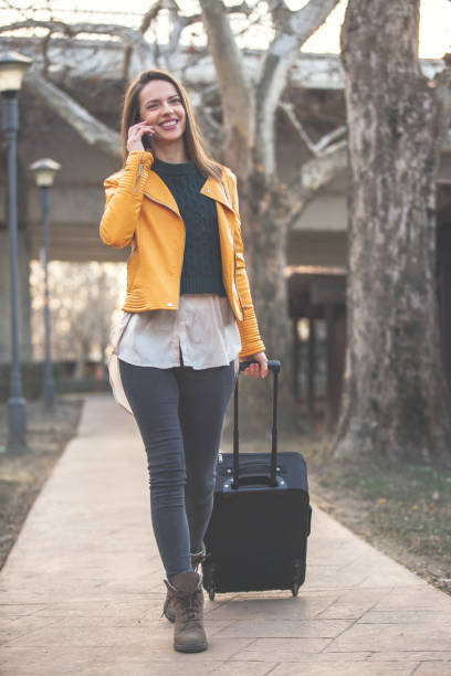 istock Young woman with suitcase talking on mobile 1137846452