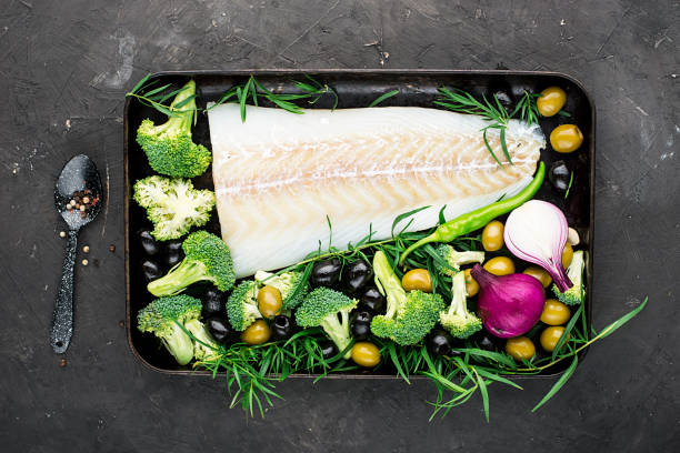 건강에 좋은 음식: 브로콜리, 타 라 곤, 양파, 올리브가 들어 있는 야생 유기농 신선한 바다 흰 대구 생선을 베이킹 시트에 담 습니다. 다이어트 가벼운 식사의 개념입니다. 평면도 - vegetable balance baking cooking 뉴스 사진 이미지