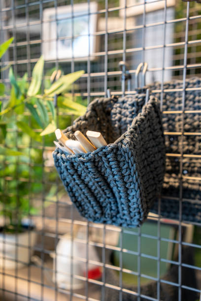 Grey crochet with tie pattern for mini tools and brush hanging on grid metal net background.