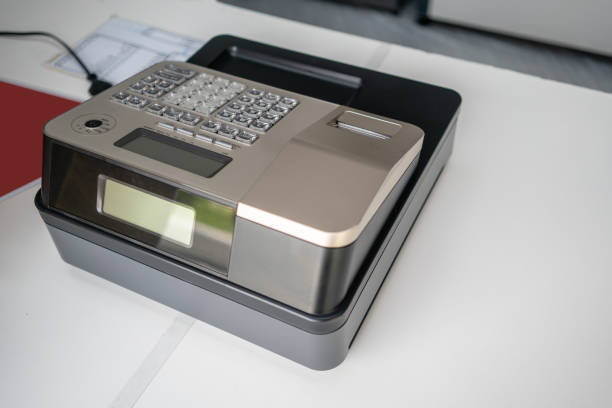 Silver cash register on white counter. Portable model cashing machine on white.