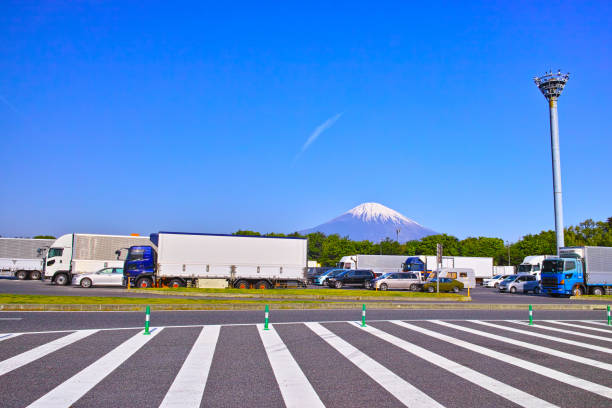 Heavy truck and passenger car parked in the service area of a Japanese highway