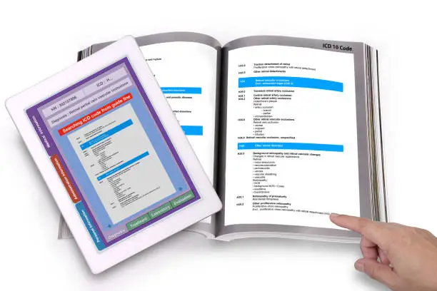 Digital tablet showing medical record technology application searching ICD code on screen and medical ICD code guide book on white bacjground.
