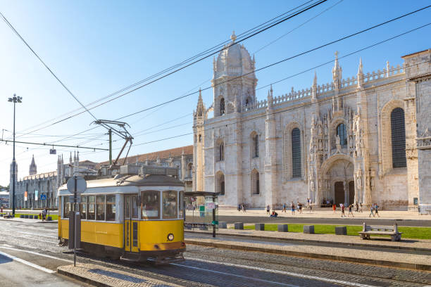histórico tranvía amarillo clásico de lisboa construido parcialmente de madera frente al famoso monasterio de los jerónimos - cable car lisbon portugal portugal old fotografías e imágenes de stock