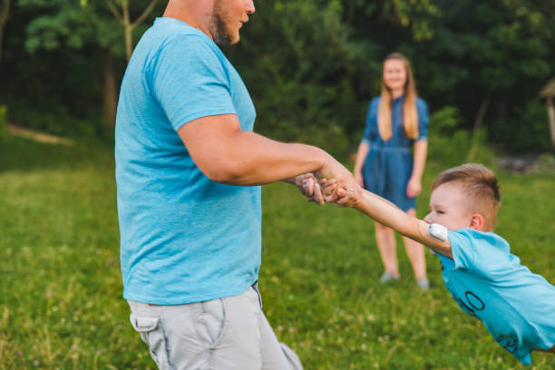 istock man spinning boy at green field. playing around 1137883545