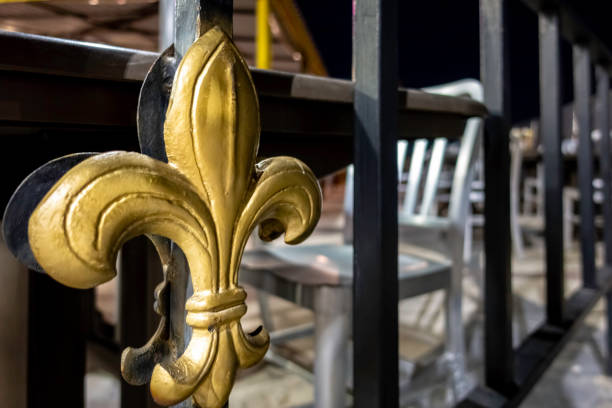 An ornate Fleur de Lis symbol on a railing fence along a public walkway An ornate Fleur de Lis symbol on a railing fence along a public walkway. The symbol is made of metal painted golden in color. The Fleur de Lis is a state emblem adopted by the American State of Louisiana. new orleans fleur de lis stock pictures, royalty-free photos & images
