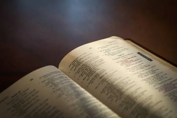 Open bible on a dark wood table with light and focus on Psalm 27