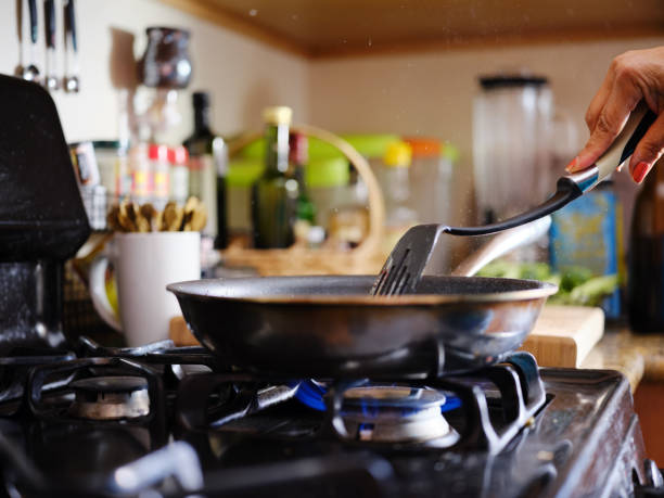 stirring strips of beef in hot skillet inside home kitchen on gas stove stock photo