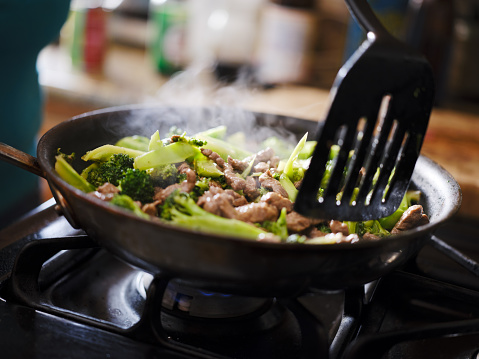 cooking beef and broccoli stir-fry in hot pain inside home kitchen shot with selective focus