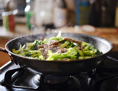 freshly cooked beef and broccoli stir-fry in hot skillet shot with selective focus