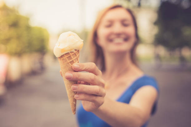 istock Summertime: Young smiling woman is eating ice cream 1137896832