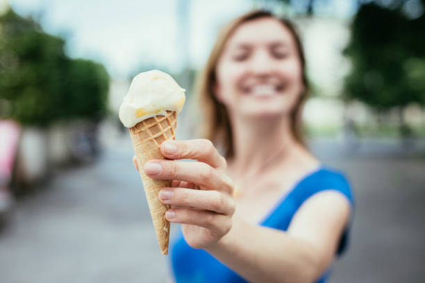 istock Summertime: Young smiling woman is eating ice cream 1137896835