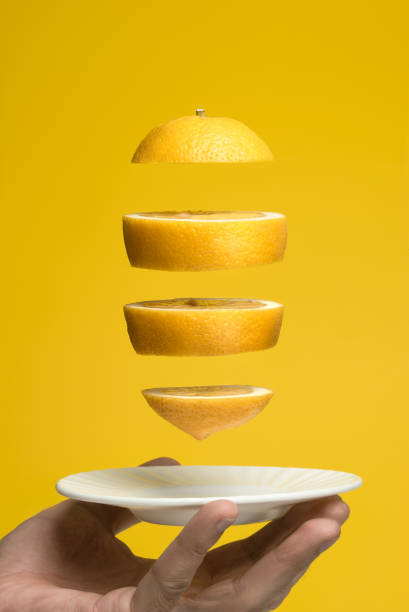 istock Flying lemon slices over a white saucer. Yellow background. 1137898805