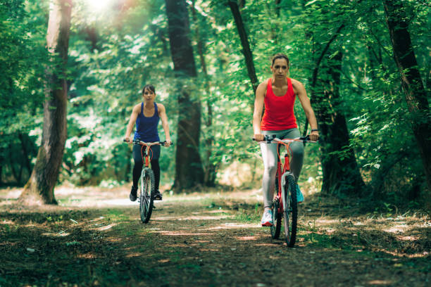istock Two Women Riding Bicycle In Forest 1137906145