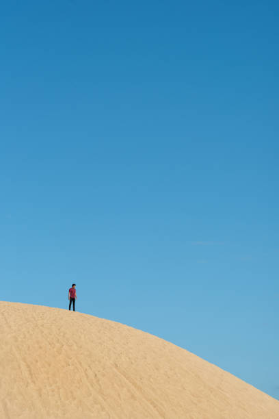 istock Low Angle View Of Man Standing On Sand Dune Against Blue Sky 1137907305