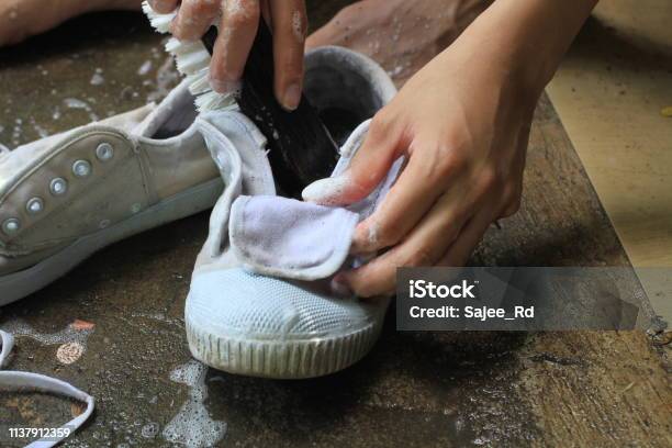 Boy Washes A Pair Of Dirty White Shoes Sneakers By Hands With Brush Cleaning Shoes At Home Stock Photo - Download Image Now