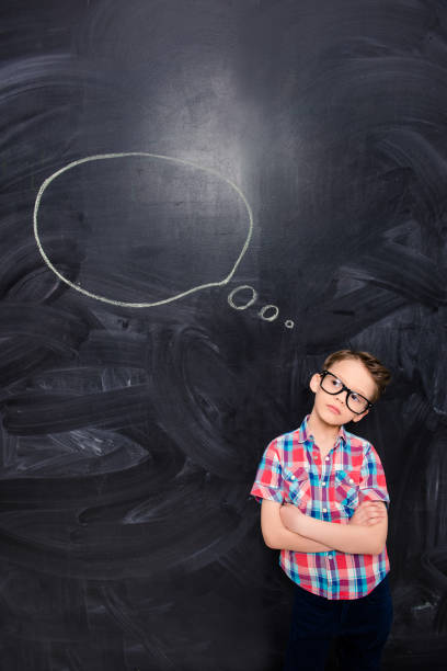 istock Young child on the background of chalkboard thinking about smth 1137914330