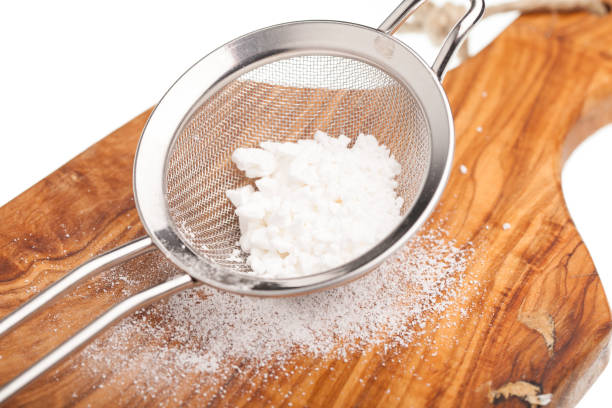 Powdered confectioners sugar in sieve.  Closeup over pastel blue background.
