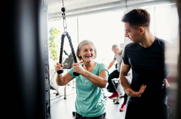 istock A female senior with a young trainer doing strength workout exercise in gym. 1137917219