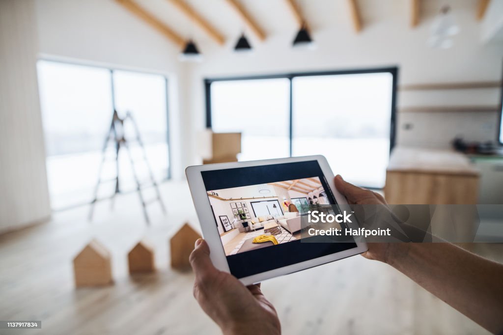 Midsection of man with tablet, looking at interior design sketches. A new home concept. A midsection of man with tablet, looking at interior design sketches. A new home concept. Real Estate Stock Photo