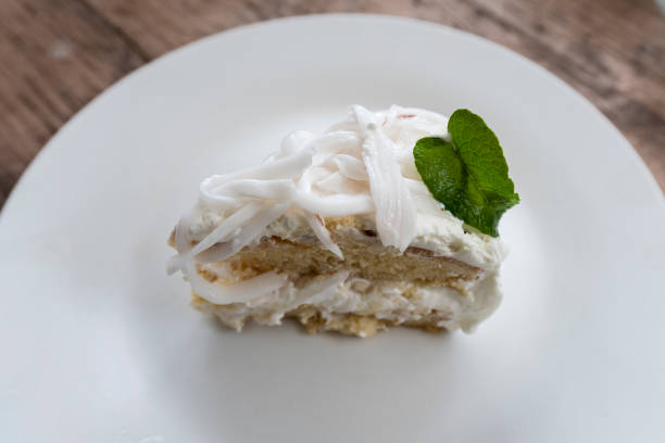 istock Coconut cream cake on a white plate with whipped cream and decorated. 1137919845