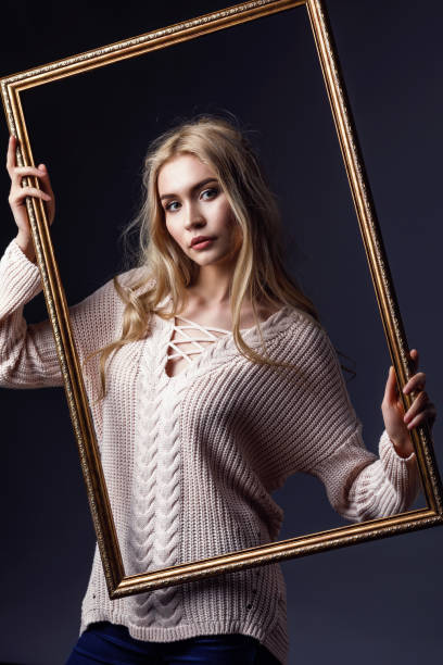 istock Young girl posing with a frame from the picture on a dark background 1137920035