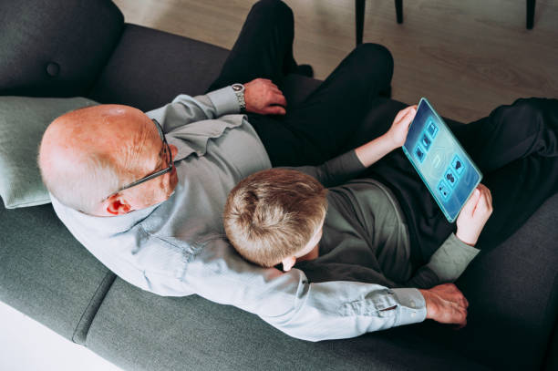 smart-home-app auf digitalem tablet hilft familienkontrollgegenständen im haus - senior adult digital tablet domestic life learning stock-fotos und bilder