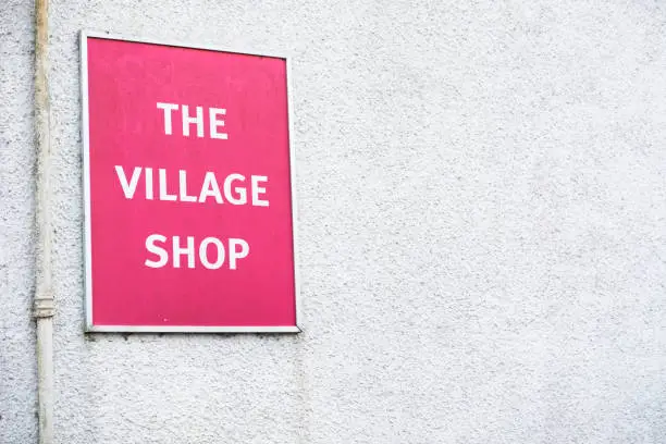 Village shop sign red on white wall background uk