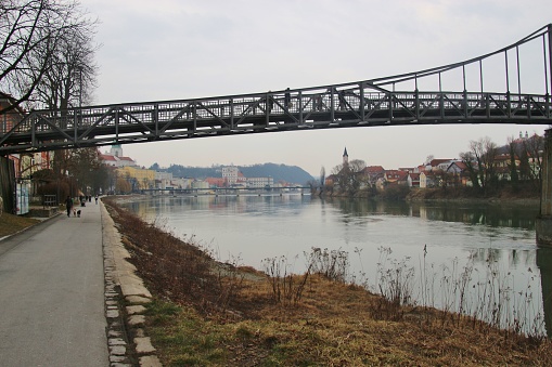 The pedestrian steel bridge Innsteg or Fünferlsteg in Passau, Germany. It connects the old town of Passau and the district Innstadt. The cityscape of Passau in the background. Europe.