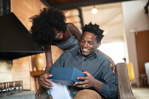 African descent brazilian couple exchanging gifts at home.