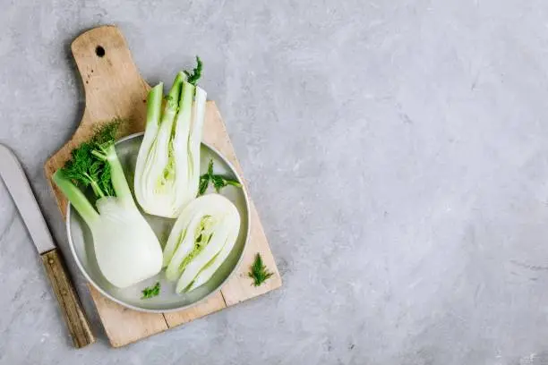 Fresh raw organic florence fennel bulbs or fennel bulb on gray stone background. Top view