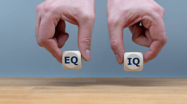 정서적 지능과 지능 몫 사이의 균형의 상징.  손은 회색 배경 앞에 문자 "eq"와 "iq"와 두 개의 주사위를 들고 있다. - equitable 뉴스 사진 이미지