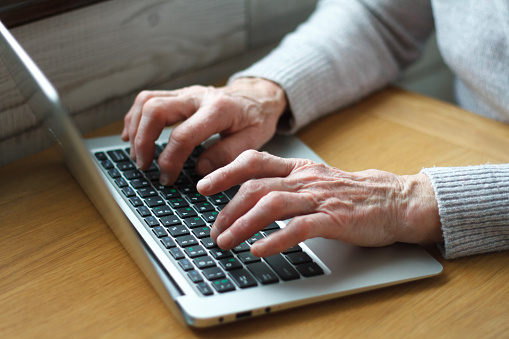 Mature female hands typing text on keyboard, senior elderly business woman working on laptop, old or middle aged lady using computer concept writing emails, communicating online, close up view.