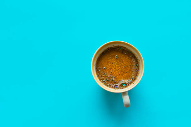 istock White cup of freshly brewed coffee with bubbly crema on solid blue background. Top view. Morning breakfast energy fashion business concept. Minimalist style. Design element and template 1137935333