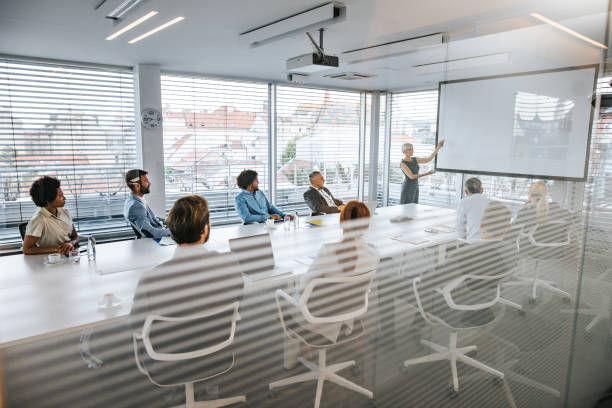 istock Senior CEO giving a business presentation through projection screen in a board room. 1137940943