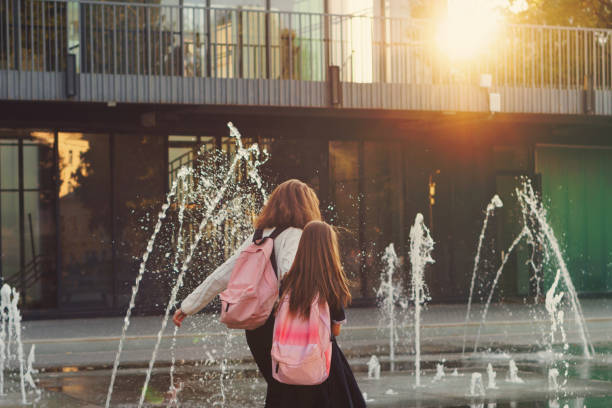 istock Sisters walk by city fountain 1137943263