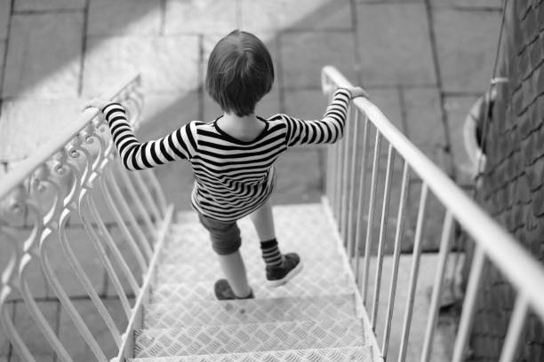 A child comes down the metal stairs from the top floor of the building
