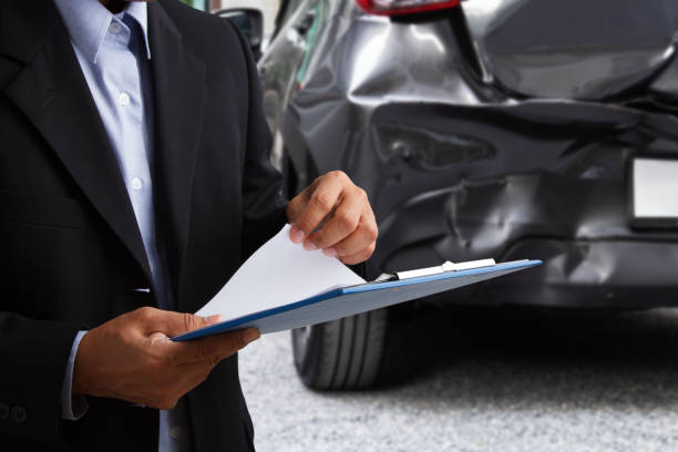 istock insurance officer writing on clipboard while insurance agent examining black car after accident. 1137944226