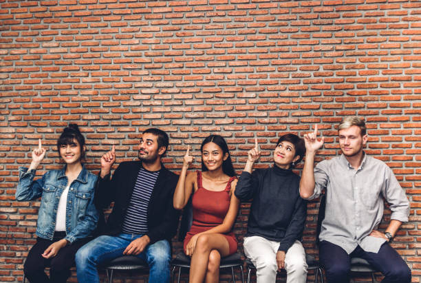 istock Group of business people while sitting on chair pointing to empty copy space against wall background 1137947521