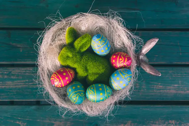 Colored easter eggs in a bowl standing on a green wooden bench, Amsterdam the Netherlands, 23 march 2019