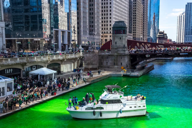 crowds gather along wacker drive, the riverwalk and on a boat to celebrate st. patrick's day in chicago along a dyed green chicago river - skyscraper travel people traveling traditional culture imagens e fotografias de stock
