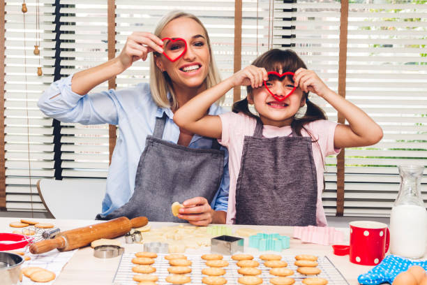 istock Mother and daugthter having fun cooking togather and learning to make a cake while baking in kitchen at home 1137953799