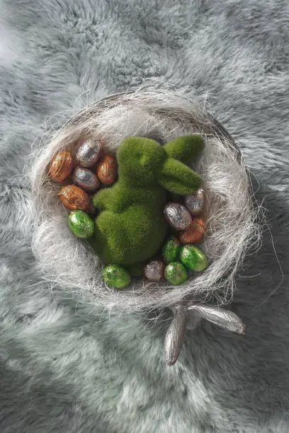 Colored easter eggs easter bunny in a bowl standing on a green wooden bench, Amsterdam the Netherlands, 23 march 2019