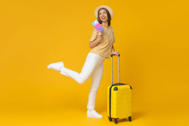 Funny girl jumping, holding suitcase and passport with flight tickets, isolated on yellow background Funny girl jumping, holding suitcase and passport with flight tickets, isolated on yellow background jump jet stock pictures, royalty-free photos & images