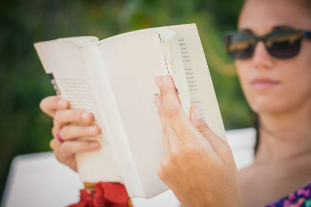 istock Woman reading book while enjoying the sunshine at the beach 1137958596