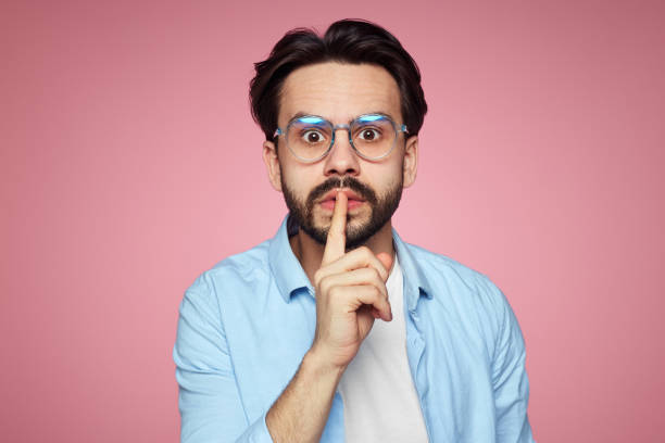 istock Attractive man shows hush gesture, looks with stunned expression at camera, afraids of gossiping, isolated over pink background. 1137960439