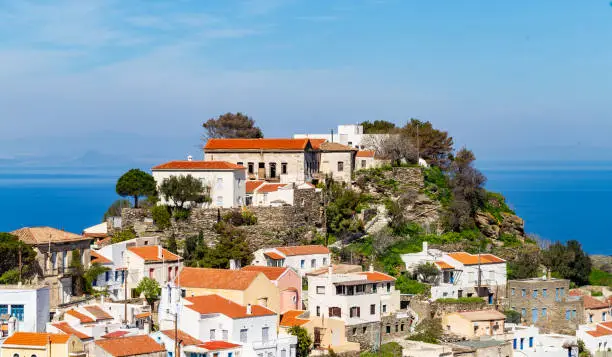 Greece, Kea island. Kastro area in Tzia capital city, Ioulis. Traditional buildings with red roofs, blue sky and sea background